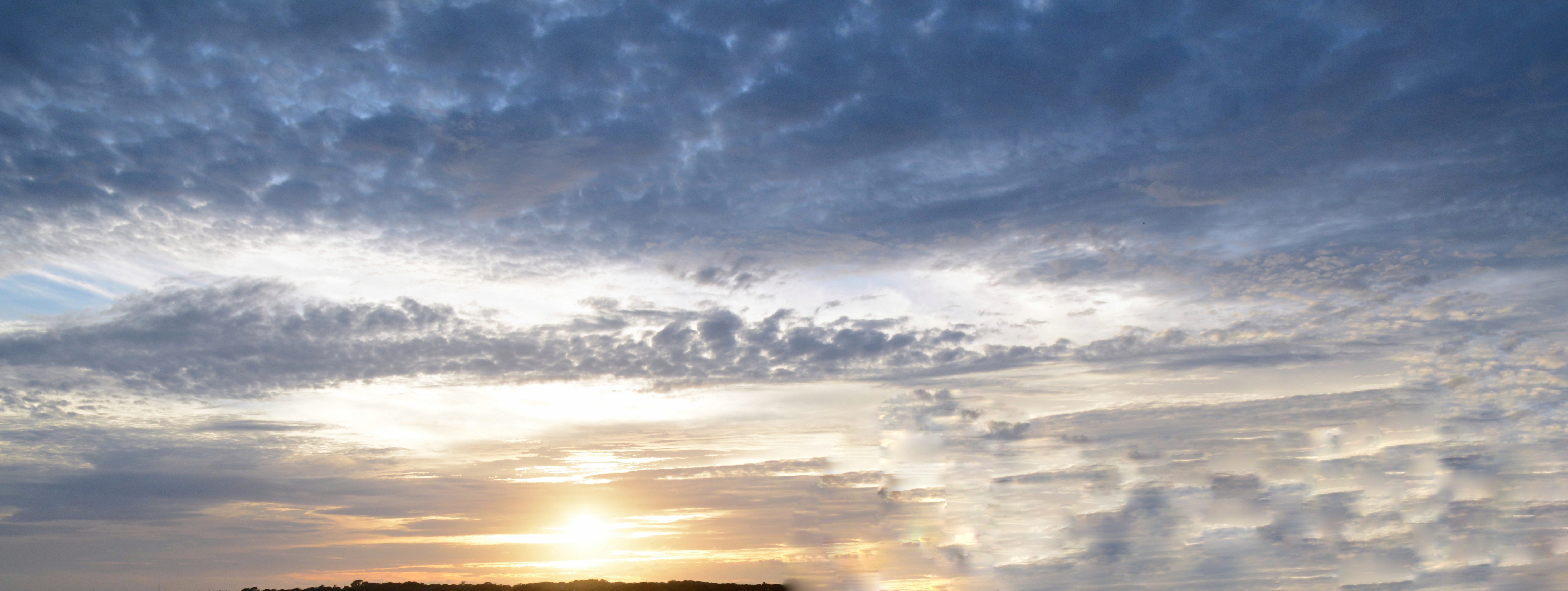 Dramatic cloudy sky with warm sunlight over the horizon